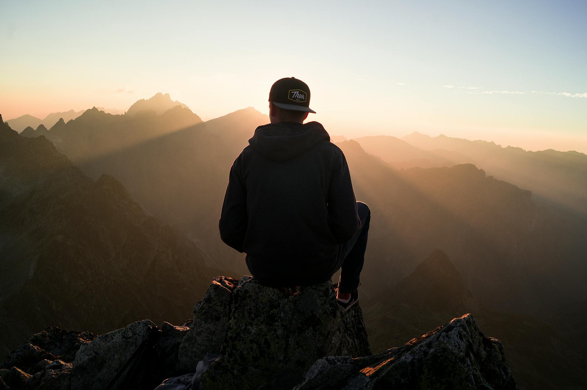 man sitting on the mountain edge